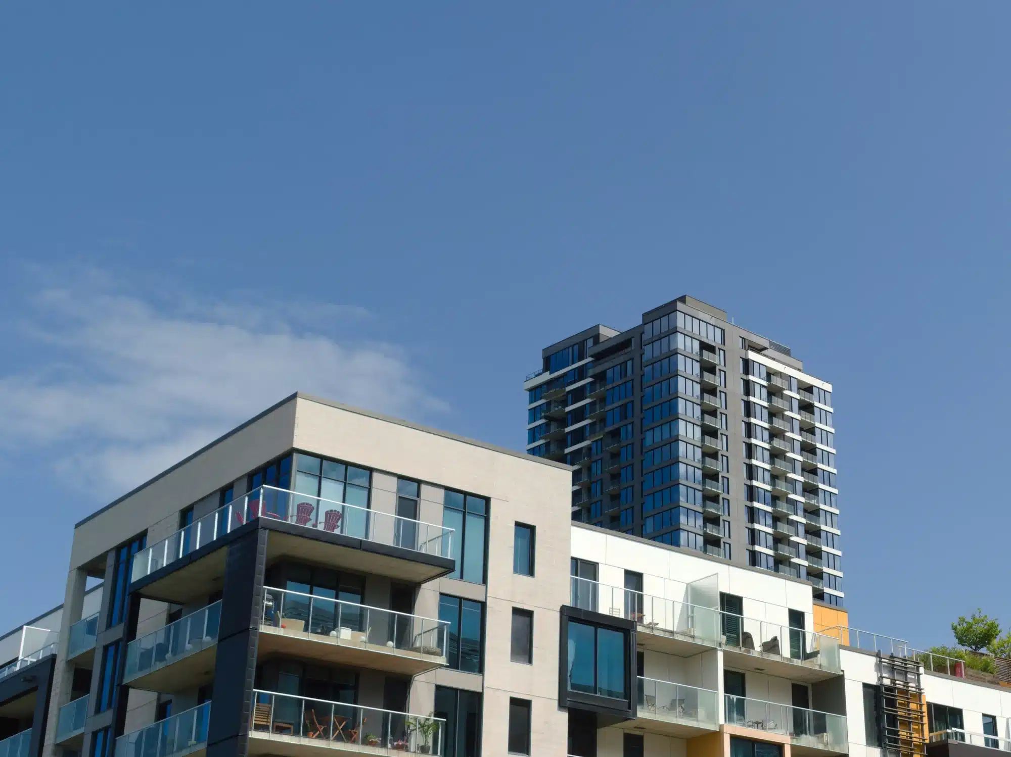Modern multi-story apartment buildings with balconies under a clear blue sky.